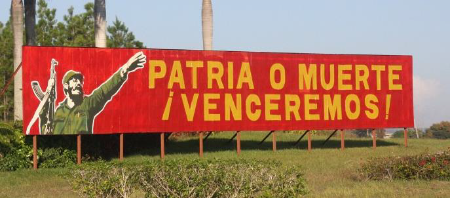 A billboard in Cuba depicting Fidel holding an AK-47 rifle, with the motto “patria o muerte, ¡venceremos!” meaning “fatherland or death, we will win!”